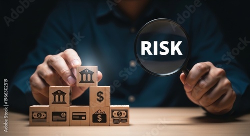 Magnifying glass examining wooden blocks with financial icons, symbolizing risk assessment and management in banking.