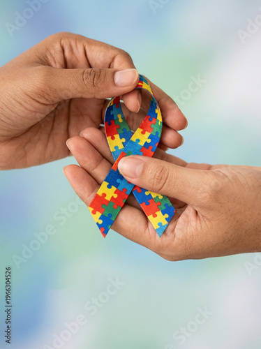 Hands holding an autism awareness puzzle ribbon