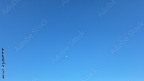 Minimalist Clear Blue Sky Background with Small Moon Shining in Bright Daylight