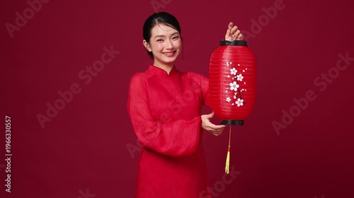 Asian woman holding decorative red lantern, smiling, traditional New Year theme for festive visual content.