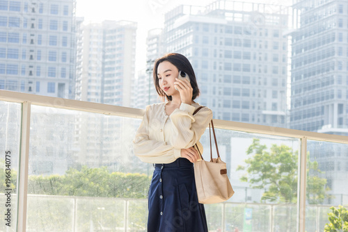 A portrait of an Eastern businesswoman, an urban white-collar worker, using her mobile phone Free Download A portrait of an Eastern businesswoman, an urban white-collar worker, using her mobile phone - GFXLoad