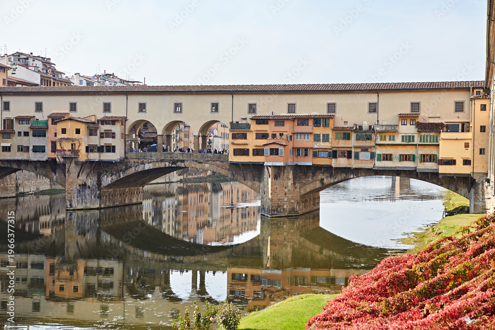 Fototapeta premium Historic arched bridge over a river with old buildings reflected in calm water