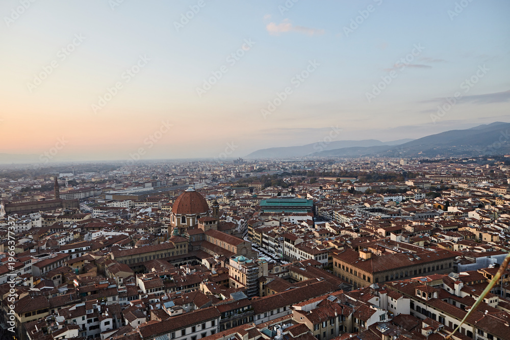 Obraz premium Panoramic view over a historic European city with dense rooftops at sunset
