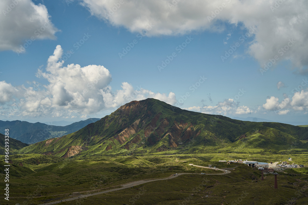 Fototapeta premium Vast volcanic landscape with green mountains, crater terrain and dramatic summer clouds