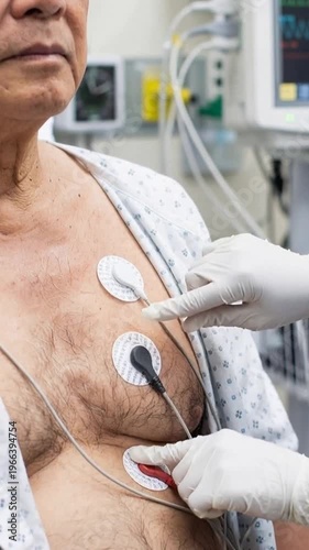 Technician adjusting cardiac monitoring electrodes on senior ecg patient in hospital room
