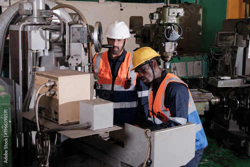 Bilde på lerret Workers operate machines in a factory during daylight hours while wearing safety