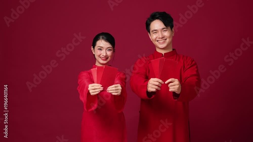 Asian couple holding red envelopes together, smiling, classic Lunar New Year greeting concept