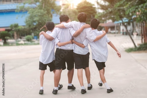 Four High School Friends Walking with Arms on Shoulders on Campus.Concept of best friends