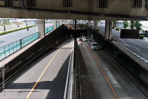 Фотография Sunlit underpass roadway receding beneath layered urban infrastructure
