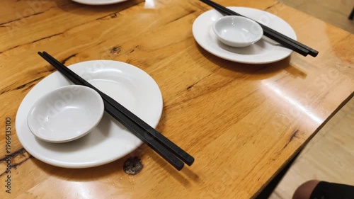 Asian Dining Aesthetics features minimalist setting with chopsticks and white ceramic on wooden table. Modern cafe interior shows Asian Dining Aesthetics for peaceful evening dinner.