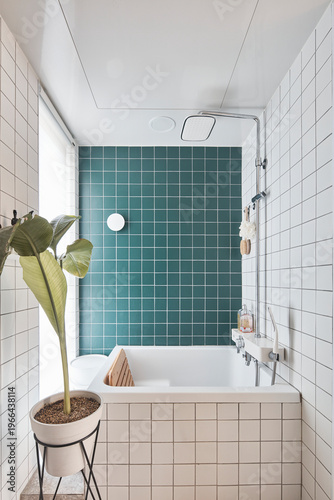 Bright tiled bathroom with green accent wall and potted plant