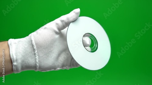 A gloved hand holds a blank optical disc against a vibrant green background, showcasing a digital storage medium