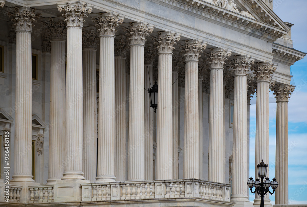 Fototapeta premium Columns stone architectural perspective symmetry. Columns marble fluted repetition. Columns decorative capitals carved detail. Columns classical facade.