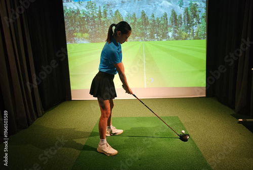 Practicing golf swing indoors at a virtual driving range
