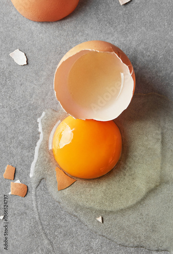 Cracked egg with yolk and shell on grey background