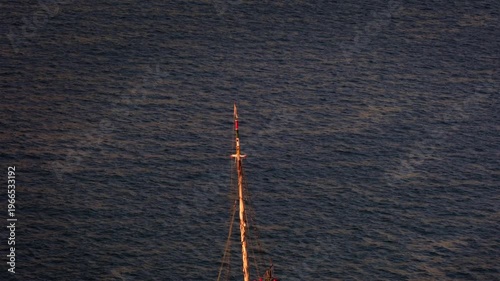 Traditional sailboat navigate calm waters at sunset 
