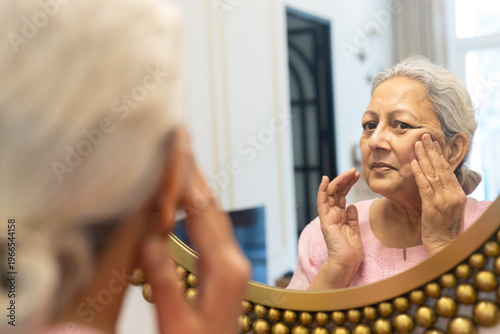 Senior indian woman touching face check facial wrinkles looking in mirror reflection, Old mature 60s female concern about her face skin. Aging process.
