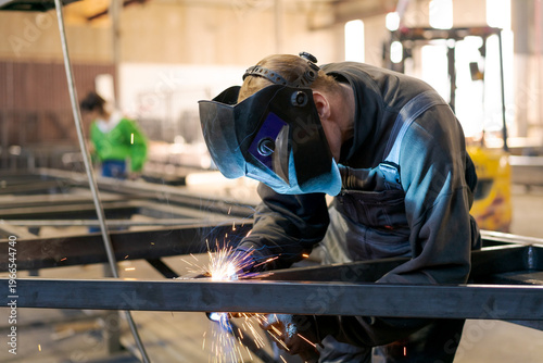 Canvastavla Welder in Protective Mask Welding Steel Structure with Sparks