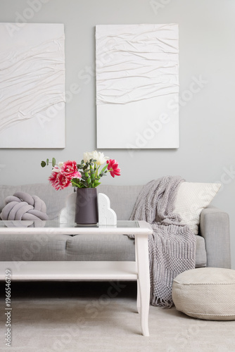 Interior of living room with sofa, table and tulips in vase for Women's Day