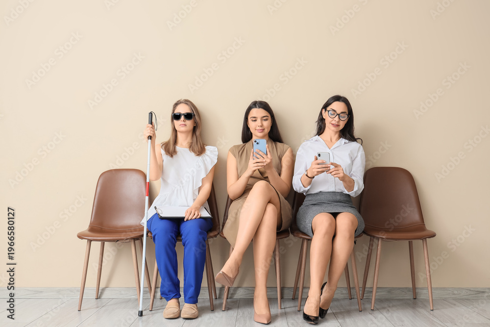 Obraz premium Job applicants with blind woman waiting for interview near beige wall