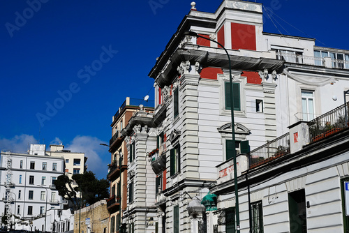 decorative classic old white stucco exterior elevation closeup in Naples, Italy. retail stores and offices at street level. blue sky and white clouds. architecture, culture, travel and tourism concept