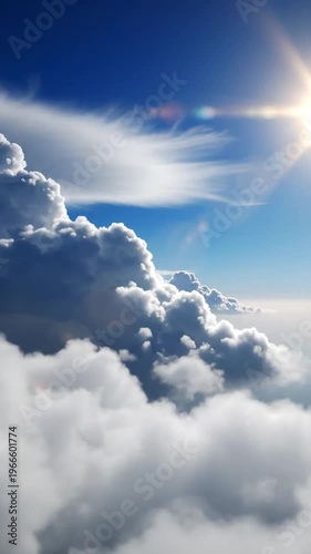 Vast blue sky filled with dramatic, fluffy white clouds illuminated by a bright, warm sun with lens flare