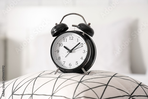 Alarm clock on pillow in be...