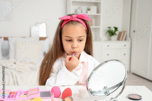 Cute little girl using cosm...