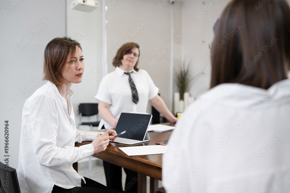 Fototapeta premium Girl in white shirt writing notes while talking with team during business breakfast at office. Writing, business, notes, breakfast, teamwork, meeting.