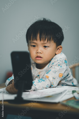 Toddler Watching Smartphone While Drawing at Table
