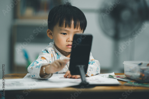 Toddler Watching Smartphone While Drawing at Table