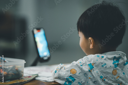Toddler Watching Smartphone While Drawing at Table