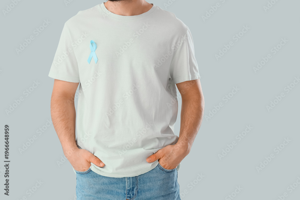 Obraz premium Young man with blue ribbon on light background. Prostate cancer awareness concept