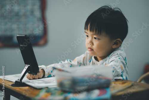 Toddler Watching Smartphone While Drawing at Table