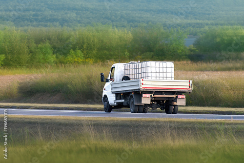 Work truck delivering liquid storage container rurally
