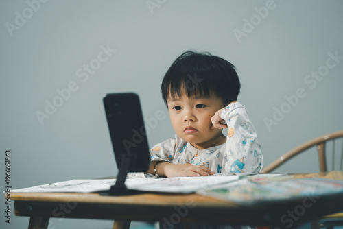 Toddler Watching Smartphone While Drawing at Table