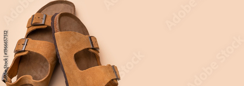 Stylish summer leather sandals on gray background, top view. Brown unisex flip-flops made of genuine nubuck leather with cork sole for beach and travel. Fashionable footwear, minimalist layout