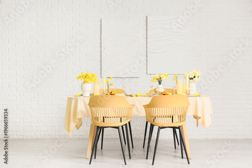 Elegant table setting with beautiful narcissus flowers in light dining room