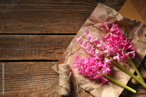 Beautiful pink hyacinth flowers with envelopes and supplies on brown wooden background