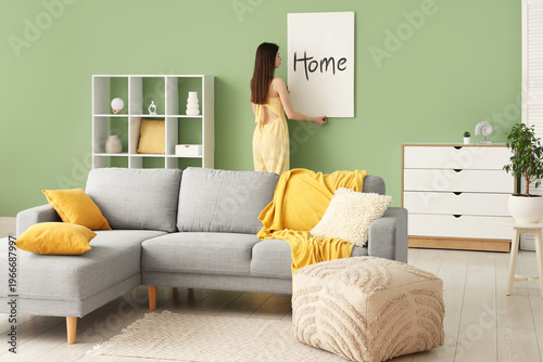 Young woman hanging picture...