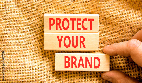 Protect your brand words symbol. Concept words Protect your brand on beautiful wooden blocks. Beautiful canvas background. Businessman hand. Business and protect your brand concept. Copy space.