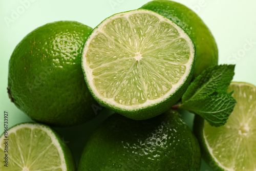 Fresh limes with mint on green background