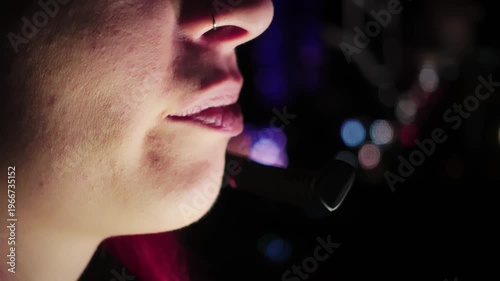 Closeup of mouth articulating persuasive sales language at night. Young adult Caucasian lady is talking by call using headphones focused on closing deal during late evening. Theme of being freelancer 