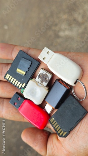 USB Flash Drive Collection in Hand, Data Storage and Portable Technology Concept. Close up of hand holding multiple USB flash drives. Collection of various USB flash drives and SD memory cards