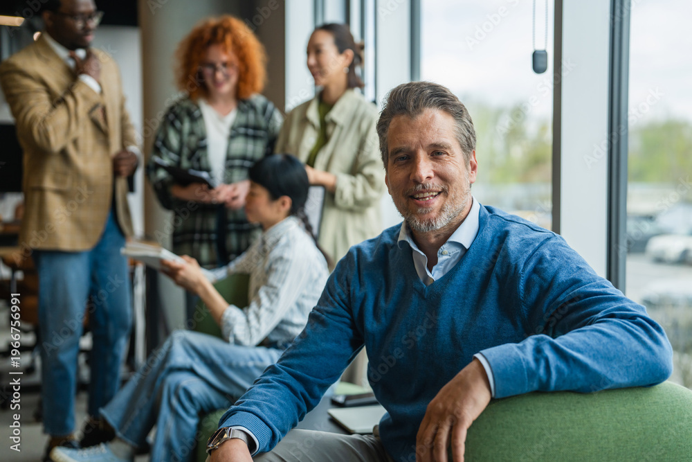 Obraz premium Mature businessman smiling with diverse team in modern office