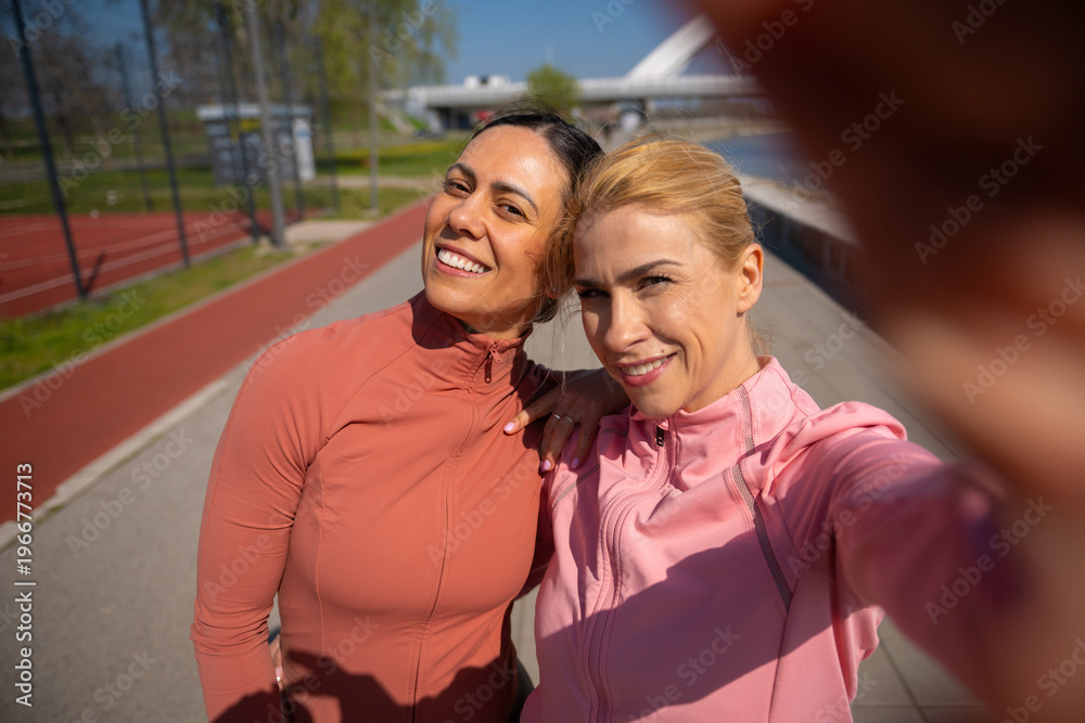 Naklejka premium Women friends taking selfie on running track