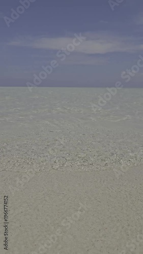 Video of waves crashing on a calm beach, the sand is visible because the sea water is very clear