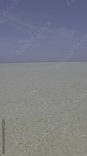 Video of waves crashing on a calm beach, the sand is visible because the sea water is very clear