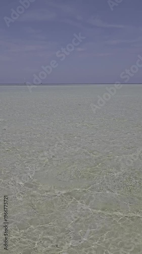 Video of waves crashing on a calm beach, the sand is visible because the sea water is very clear