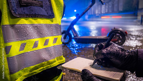 High visibility police vest and notebook in wet conditions near an electric scooter at night in the UK